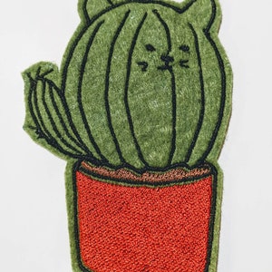 May include: A green felt cactus with a cat face embroidered on it, in a red felt pot.