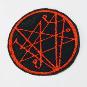 May include: A black and red embroidered patch with a pentagram design.