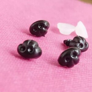 May include: Five black plastic safety eyes with a screw back. The eyes are heart-shaped and have a raised, textured surface.