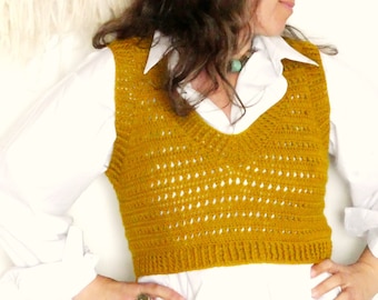 May include: A mustard yellow crocheted vest with a V-neckline. The vest is cropped and has a lacy pattern.
