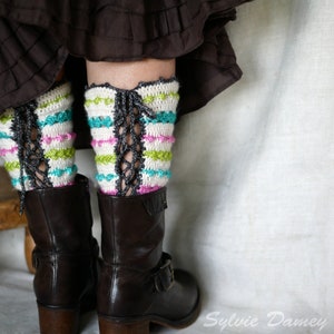 May include: Crocheted leg warmers with a lace-up back detail in white, pink, green, and blue. The leg warmers are worn with brown leather boots.