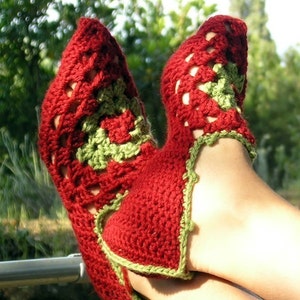 Puede incluir: Pantuflas de crochet rojas y verdes con un diseño de encaje. Las pantuflas se llevan en los pies de una persona.