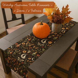 May include: A dark table runner with a witchy autumn design featuring moons, bats, and potion bottles. An orange pumpkin and fall foliage decorate the table. The text reads "Witchy Autumn Table Runner - 2 Sizes / 2 Fabrics."