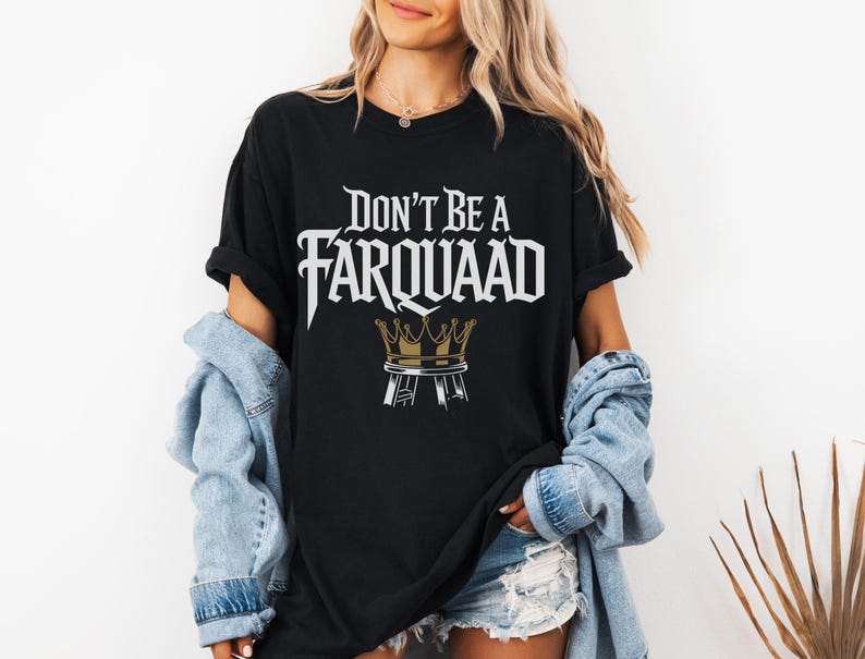 May include: Black t-shirt with the text "DON'T BE A FARQUAAD" in white, stylized font, and a gold crown graphic. The shirt is worn with a light blue denim jacket and denim shorts.