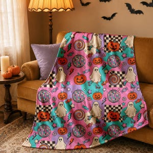 Peut inclure: Un plaid orné d'un motif répétitif de fantômes sur des patins à roulettes, de citrouilles d'Halloween, de boules à facettes, de sucettes et de bonbons. Le design inclut un damier, des éclairs et des étoiles dans des tons rose, violet et bleu sarcelle.