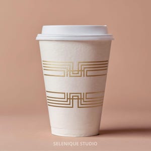 May include: A white ceramic mug with a black handle and the text "But First, Coffee" in a bold, black font. The mug is sitting on a wooden surface. The mug is approximately 4 inches tall.