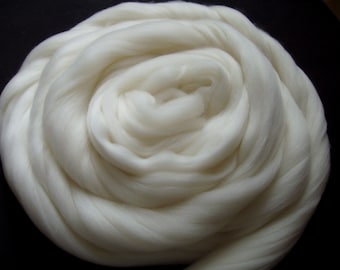 May include: A close-up of a large, white, fluffy ball of wool. The wool is arranged in a spiral pattern, creating a soft and inviting texture.