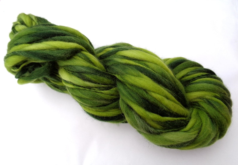 May include: A skein of green and dark green hand-dyed wool yarn. The yarn is thick and fluffy, and it is perfect for knitting or crocheting.