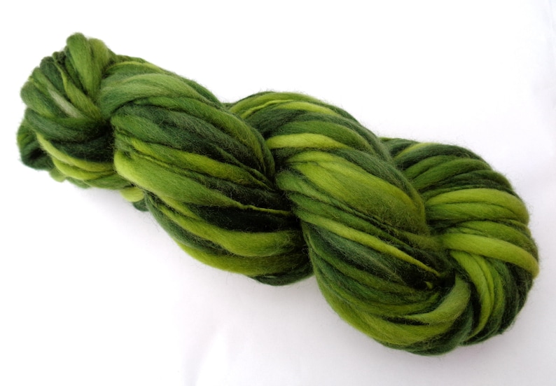 May include: A skein of green and dark green hand-dyed wool yarn. The yarn is twisted and knotted, showing the different shades of green.