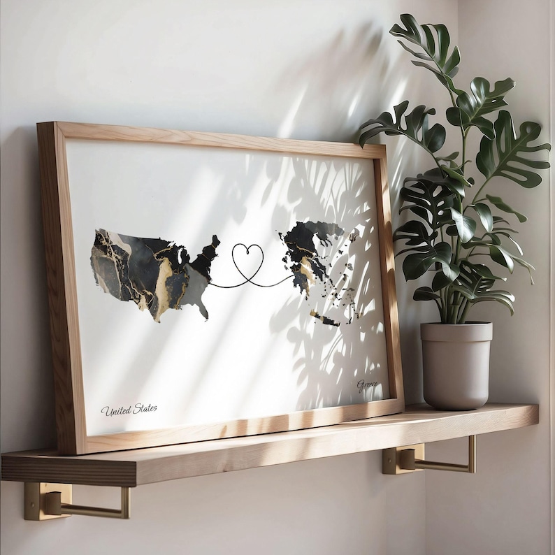 Wooden framed map print resting on a floating shelf next to a potted monstera plant, with natural shadow patterns cast across the wall.