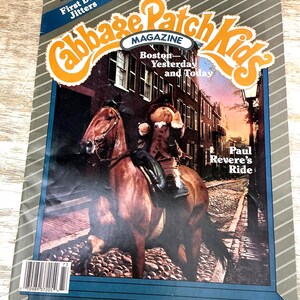 May include: A Cabbage Patch Kids Magazine from Fall 1987 featuring a doll dressed in colonial attire riding a brown horse on a cobblestone street. The cover includes the text First Day Jitters, Boston Yesterday and Today, and Paul Revere's Ride.