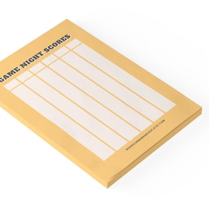 May include: A rectangular notepad with the text "GAME NIGHT SCORES" in navy blue. The notepad has a light yellow border and white interior with horizontal lines for keeping score. The website address is printed at the bottom.