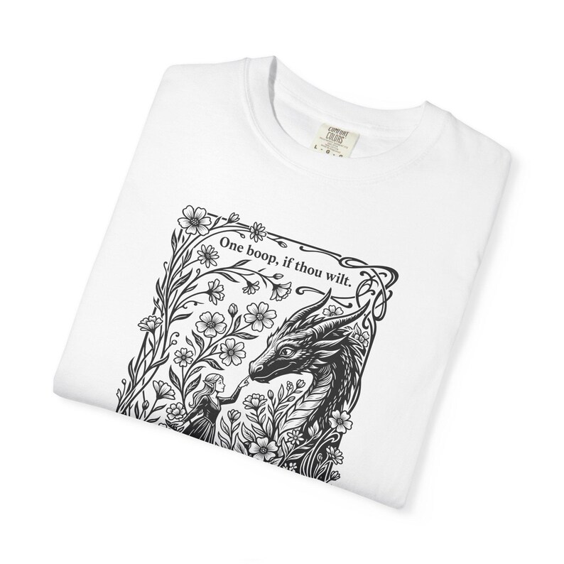 May include: A white t-shirt featuring a black ink-style graphic of a person touching a dragon's nose amidst flowers. The text above the illustration reads, "One boop, if thou wilt." The shirt has a Comfort Colors brand label at the neck.