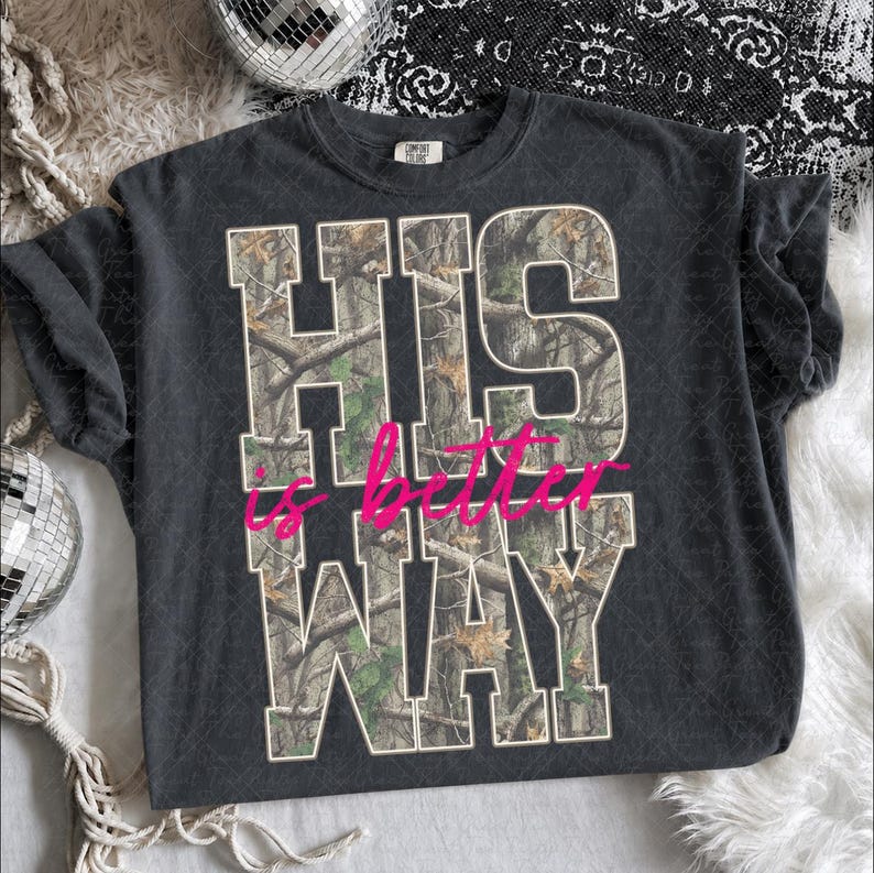 K&ouml;nnte beinhalten: Ein anthrazitfarbenes Kurzarm-T-Shirt mit dem Text HIS WAY in gro&szlig;en Blockbuchstaben, die mit einem Baum-Tarnmuster gef&uuml;llt sind. Die W&ouml;rter is better sind in einer leuchtend pinkfarbenen Schreibschrift &uuml;ber die Mitte des Designs gedruckt.