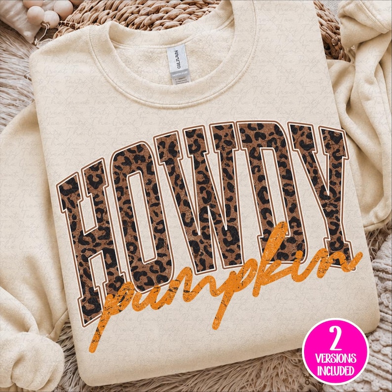 Puede incluir: Una sudadera de cuello redondo color crema que presenta la palabra HOWDY en letras grandes de estilo bloque con un patr&oacute;n de leopardo marr&oacute;n y negro. Debajo de la palabra HOWDY, la palabra pumpkin est&aacute; impresa en una fuente naranja desgastada.