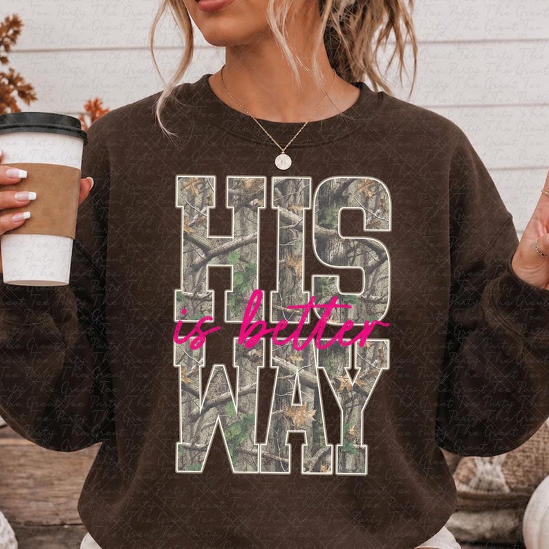 K&ouml;nnte beinhalten: Ein dunkelbraunes Sweatshirt mit Rundhalsausschnitt und dem wei&szlig;en Blockschrift-Text HIS WAY, der mit einem Tarnmuster gef&uuml;llt ist. Die W&ouml;rter is better sind in einer leuchtend pinken Schreibschrift zwischen den beiden Textzeilen aufgedruckt.