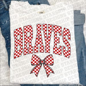 Puede incluir: Camiseta blanca con la palabra "BRAVES" en letras de bloque a cuadros rojos y blancos. Una pajarita a cuadros rojos y blancos est&aacute; debajo de la palabra. La camiseta se muestra sobre unos vaqueros azules.