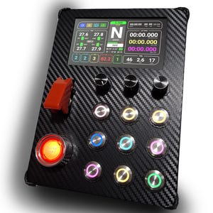 Könnte beinhalten: Eine schwarze Carbonfaserplatte mit einem Digitaldisplay und mehreren Knöpfen. Das Display zeigt verschiedene Datenausgaben, einschließlich Zahlen und Zeitinformationen. Es gibt einen großen roten Knopf mit der Aufschrift "ENGINE START" und einen roten Kippschalter.