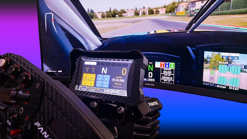 Op de afbeelding: Een close-up van een racesimulatoropstelling met een Fanatec-stuurwiel en displayschermen. De schermen tonen racegegevens, waaronder rondetijden en versnellingsinformatie. De achtergrond is een wazige afbeelding van een racebaan.