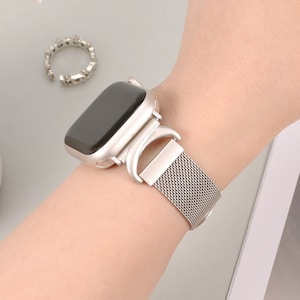 以下が含まれることがあります： 磁気留め具付きのシルバーのApple Watchバンド。バンドは細かいメッシュメタル製です。