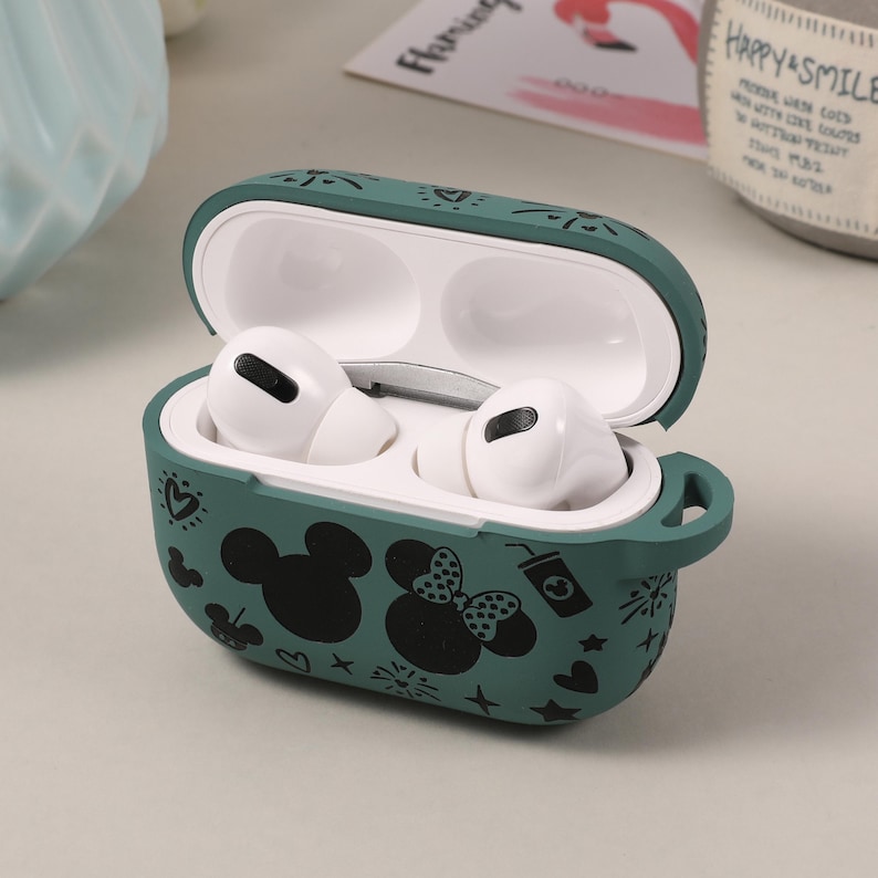 May include: A green silicone case for AirPods with a black and white Mickey Mouse and Minnie Mouse design. The case is open, revealing the white AirPods inside.