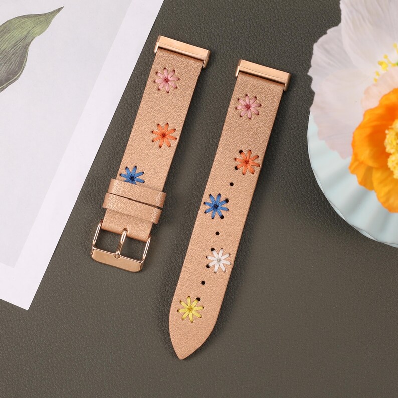 Puede incluir: Dos correas de reloj de oro rosa con un dise&ntilde;o floral. Las correas son de cuero y tienen una hebilla de oro rosa. Las flores est&aacute;n bordadas en diferentes colores, incluyendo azul, naranja y amarillo.