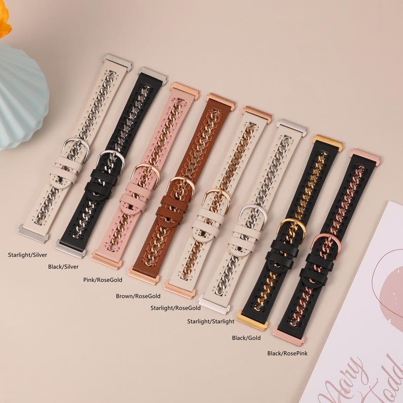 May include: An assortment of watch bands in various colors, including black, pink, brown, and white. Each band features a chain design and a buckle closure. The bands are displayed on a light-colored surface.