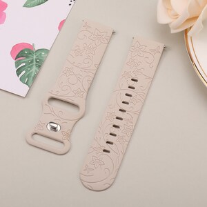 May include: Two beige silicone watch bands with a floral pattern. The bands have a buckle closure and are designed for smartwatches.
