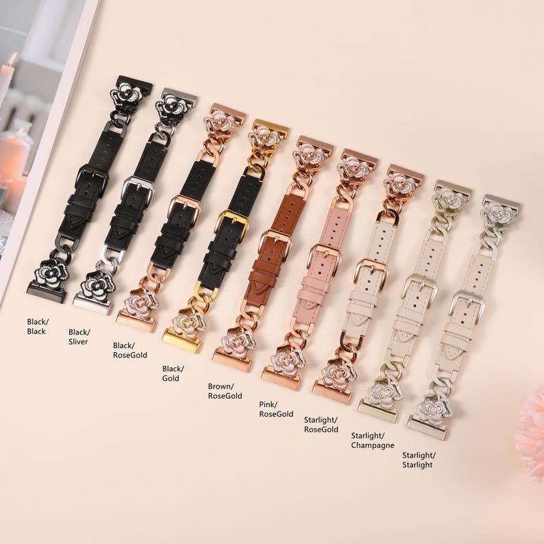 May include: A collection of watch bands in various colors, including black, silver, rose gold, brown, and pink. Each band features a decorative floral accent and a buckle closure. The bands are displayed on a light-colored surface.