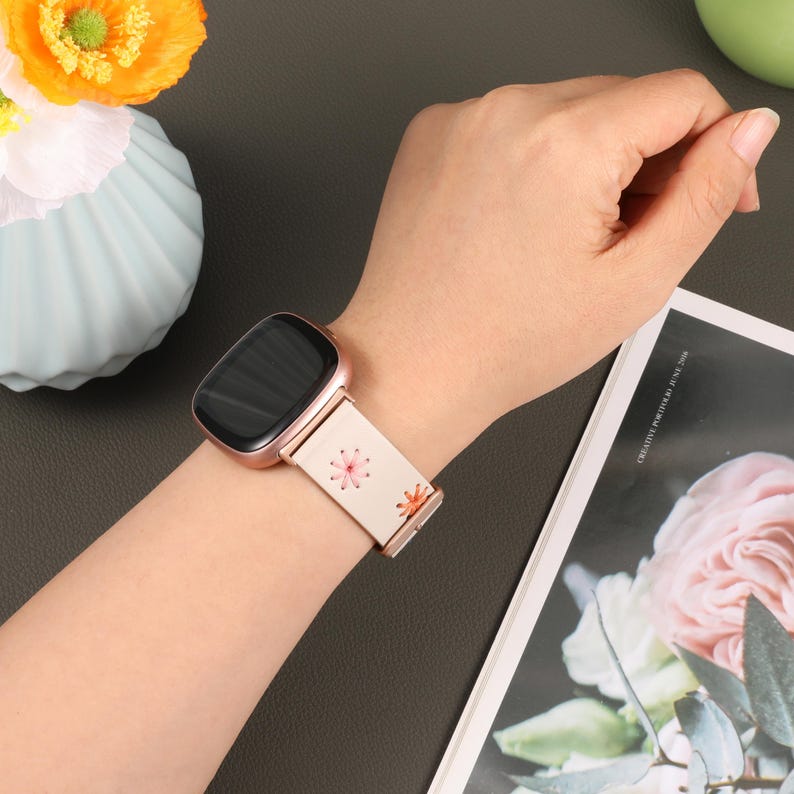 Puede incluir: Una correa de reloj inteligente blanca con un patr&oacute;n floral. La correa est&aacute; hecha de un material suave y flexible y tiene una hebilla de oro rosa. La correa es compatible con la mayor&iacute;a de los relojes inteligentes.