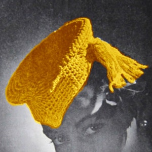 May include: A close-up of a woman wearing a yellow crocheted hat with a tassel. The hat is tilted on her head and the tassel is hanging down her back. The woman is looking down and her face is partially obscured by the hat.
