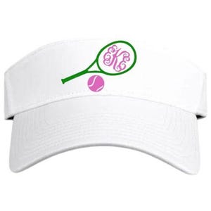 May include: White tennis visor with a green tennis racket and a pink tennis ball graphic. The racket features a pink monogram. The visor is designed to shield the eyes from the sun.