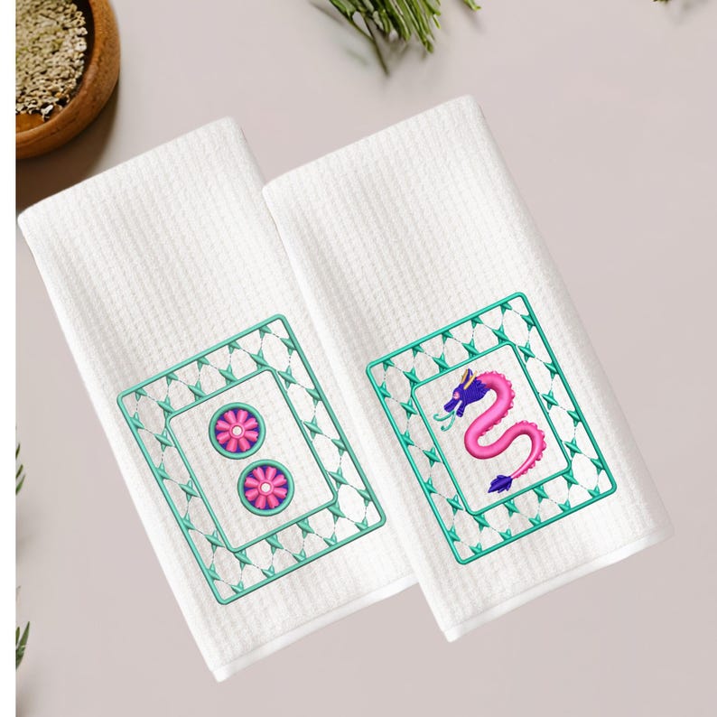 May include: Two white kitchen towels with embroidered designs. One towel features a pink flower design and the other features a purple dragon design.