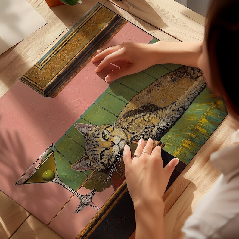 A painting of a cat laying on a green couch with a martini glass in the foreground. The cat is brown and white with green eyes. The martini glass is filled with a clear liquid and a green olive. The painting is framed in a gold frame.
