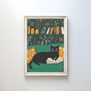 May include: A framed art print featuring a black cat lounging on a green sofa, reading a book. The background showcases a bookshelf with books and decorative items, and floral wallpaper. Orange pillows add a pop of color.