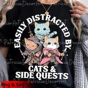 Puede incluir: Camiseta negra con un diseño de tres gatos de dibujos animados vestidos con trajes de fantasía. El texto "EASILY DISTRACTED BY CATS & SIDE QUESTS" está en blanco y en forma de arco. La imagen incluye la etiqueta "Png & Svg".