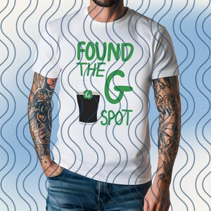 May include: White t-shirt with the text "FOUND THE G SPOT" in green. The design includes a graphic of a pint of dark beer with a green "G" on the glass. The shirt is a casual style.