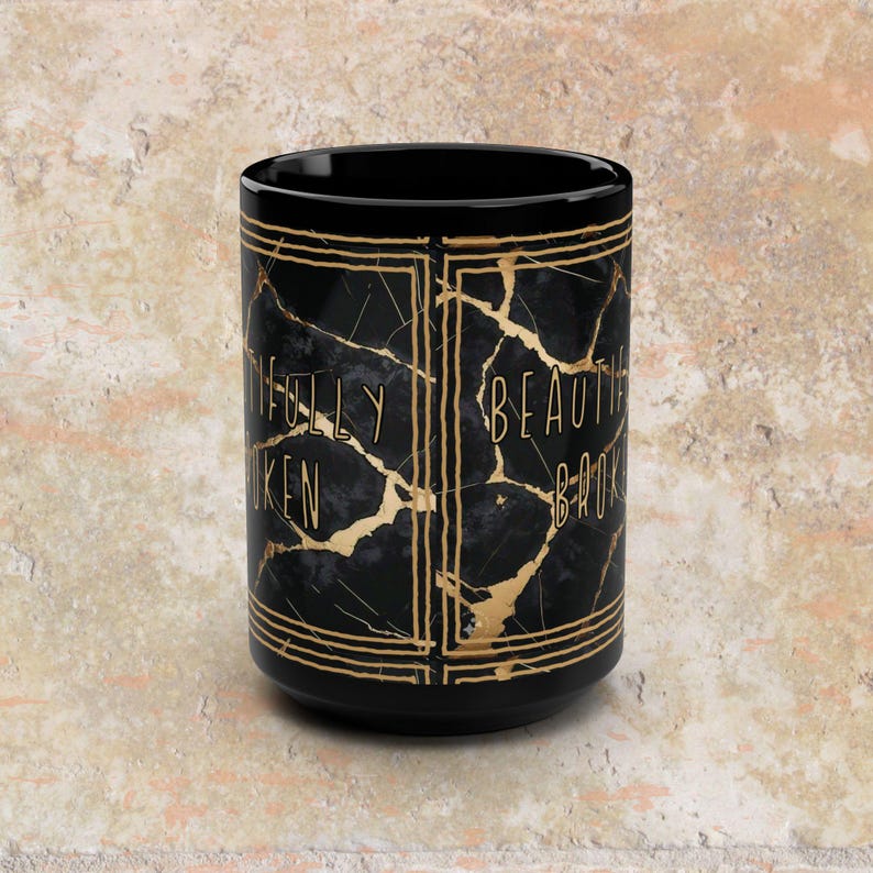 May include: Black ceramic mug with gold accents and the text "FULLY BROKEN BEAUTIFUL". The mug features a marble-like design with gold veining. The mug has a black interior and a glossy finish.