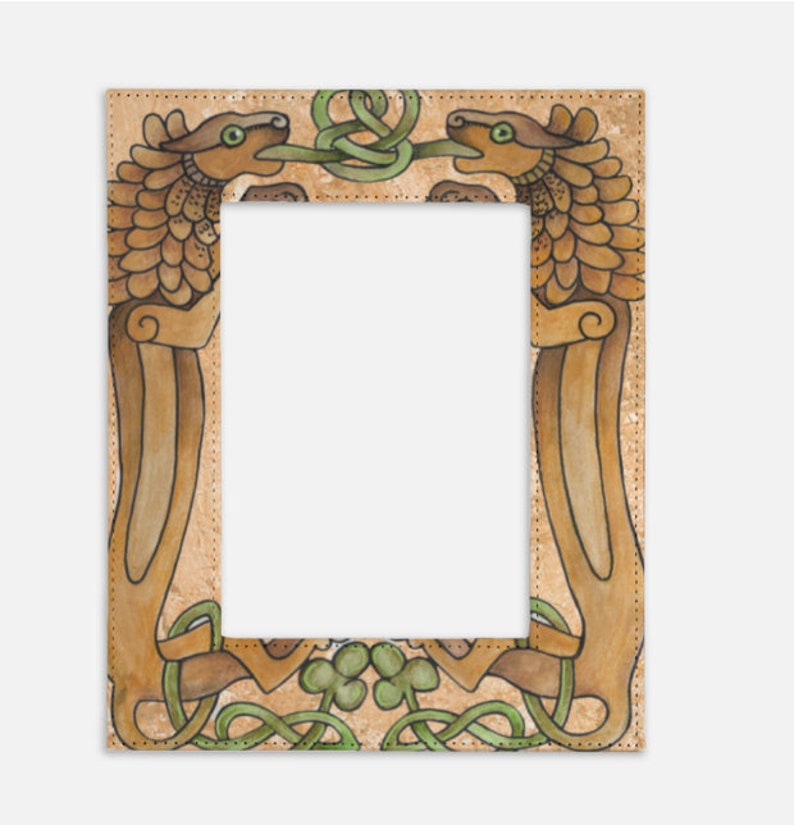 May include: A rectangular picture frame with an intricate Celtic design. Two stylized dragon-like creatures face each other, their tongues intertwined with green knotwork. The frame has a tan background with brown and green accents.