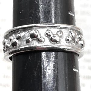 May include: A silver ring with a textured band and a repeating pattern of small, round bumps.