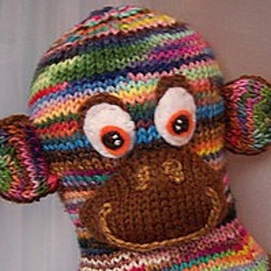 May include: A colourful knitted monkey toy with brown felt ears, a brown felt nose, and large white eyes with black pupils.