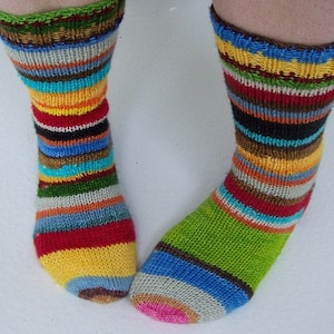 Puede incluir: Un par de calcetines de rayas coloridas con un esquema de color verde, marrón, amarillo, rojo, azul y blanco. Los calcetines están tejidos y tienen una textura acanalada.