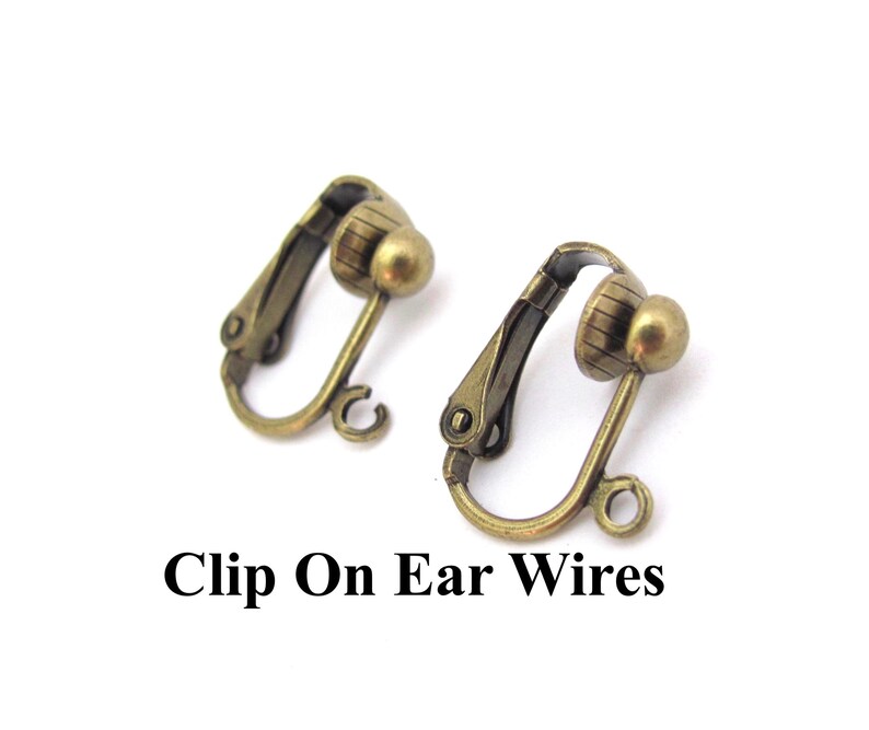 May include: Two antique brass-coloured clip-on earring findings. Each clip has a rounded ball and a hinged clip mechanism. The text "Clip On Ear Wires" is printed in black below the earrings.