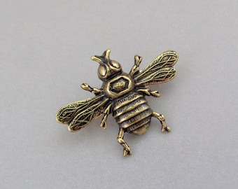 May include: A gold-toned bee brooch with detailed wings and a textured body.