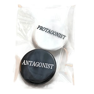 May include: Two round buttons, one black and one white, with the words "Antagonist" and "Protagonist" printed in white and black respectively.