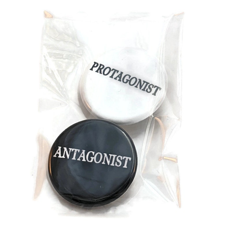 May include: Two round buttons, one black and one white, with the words "Antagonist" and "Protagonist" printed in white and black respectively.