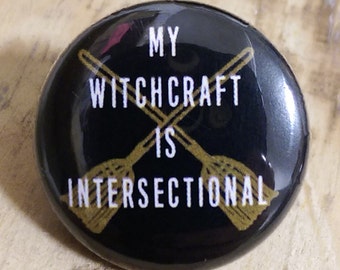Könnte beinhalten: Schwarzer Knopf mit einem goldenen Design aus zwei gekreuzten Besen und dem Text "My Witchcraft is Intersectional".