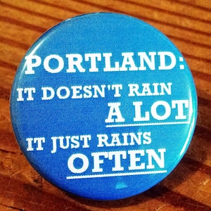 May include: A blue button with white text that reads "Portland: It doesn't rain a lot. It just rains often."