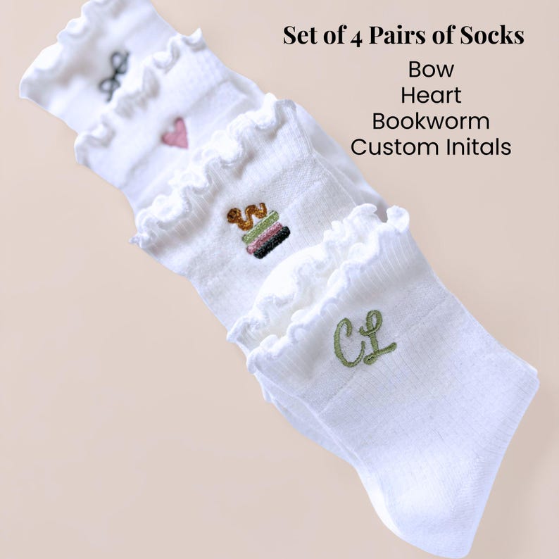 May include: Four pairs of white socks with frilled edges. Each pair has embroidered designs: a bow, heart, bookworm, and custom initials. The image text reads "Set of 4 Pairs of Socks Bow Heart Bookworm Custom Initals."