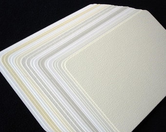 May include: A stack of white textured paper sheets, each with a slightly different shade of white.